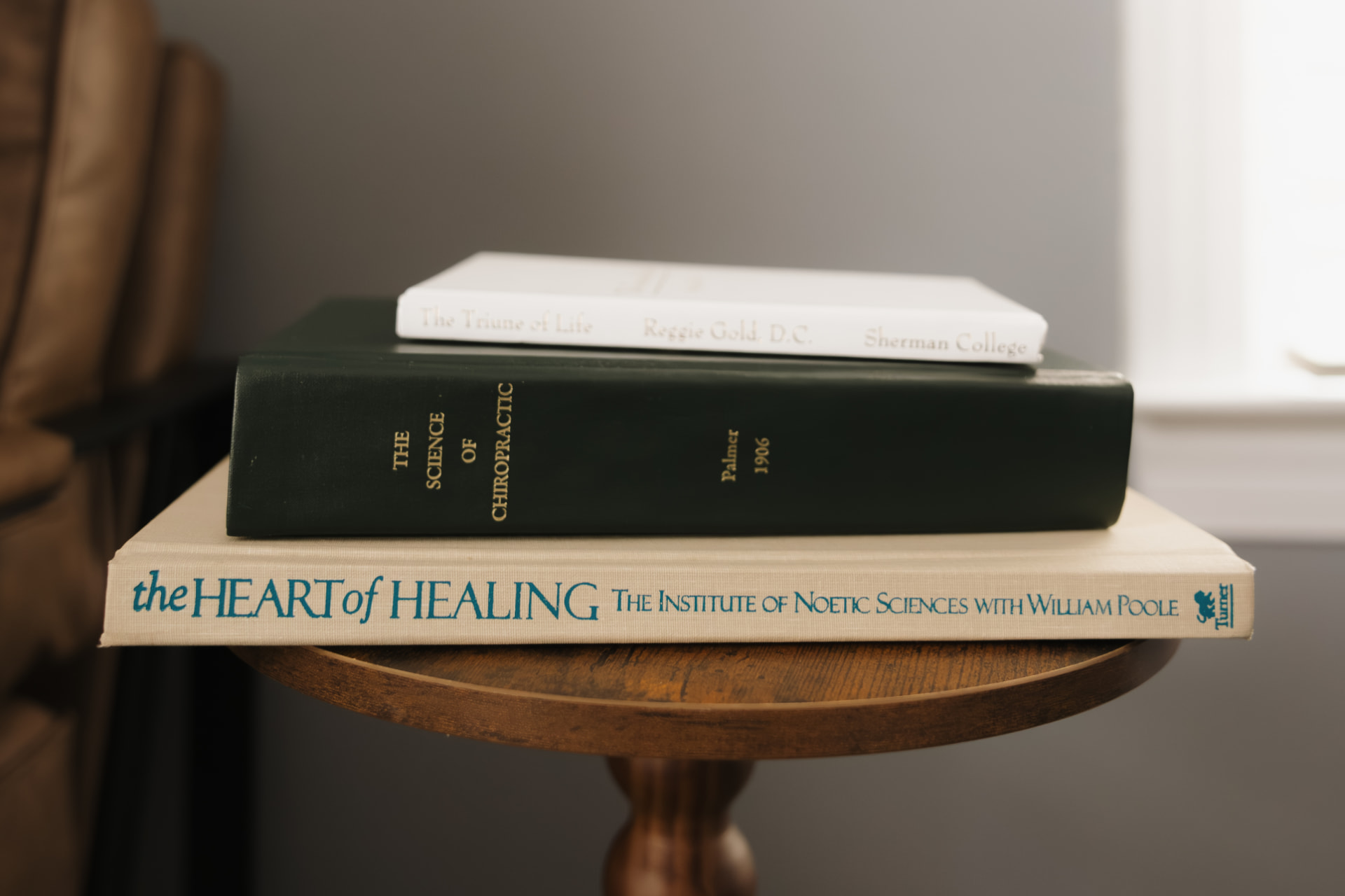 Foundational chiropractic texts stacked on a side table in the office
